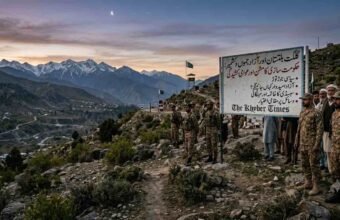 An informational sign detailing the political crisis, government formation, and public tension in Gilgit-Baltistan and Azad Kashmir, with soldiers and civilians in a mountain pass for The Khyber Times. دی خیبر ٹائمز کی خصوصی رپورٹ کے لیے گلگت بلتستان اور آزاد کشمیر میں حکومت سازی، سیاسی جوڑ توڑ اور عوامی کشیدگی کے مسائل کو ظاہر کرتا ہوا ایک معلوماتی بورڈ اور مقامی منظر۔