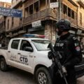 KP Police CTD personnel standing alert next to a police vehicle in Meena Bazar, Peshawar, for a Khyber Times news report.