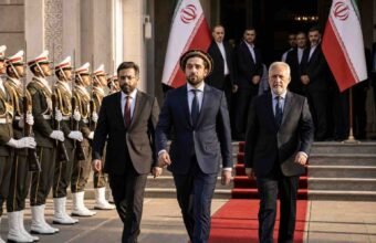 "Ahmad Massoud and the National Resistance Front (NRF) delegation walking on a red carpet at an official government reception in Tehran, flanked by Iranian honor guards."