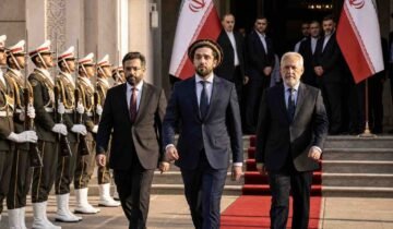 "Ahmad Massoud and the National Resistance Front (NRF) delegation walking on a red carpet at an official government reception in Tehran, flanked by Iranian honor guards."