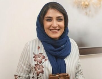 Iranian photojournalist Yalda Moaiery smiling in a navy blue scarf
