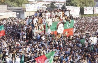 Primary Alt Text: Massive PTI power show rally with supporters holding party flags around a decorated container displaying Imran Khan's portrait.