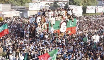Primary Alt Text: Massive PTI power show rally with supporters holding party flags around a decorated container displaying Imran Khan's portrait.