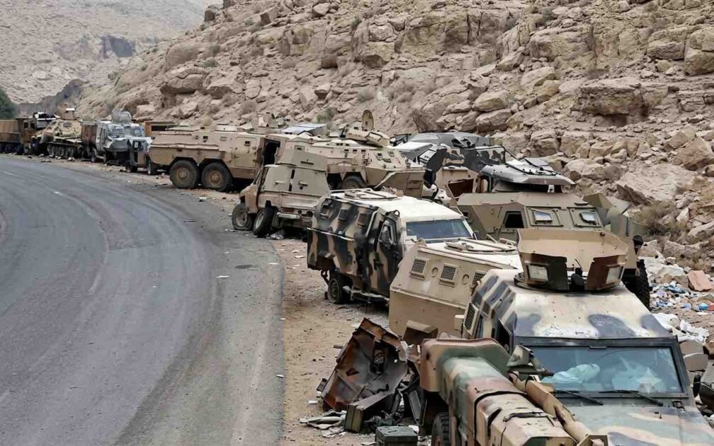 Abandoned Saudi military armored vehicles and combat equipment lined up along a mountainous road near the Yemen border.