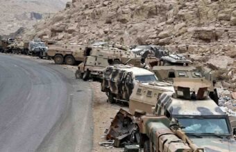 Abandoned Saudi military armored vehicles and combat equipment lined up along a mountainous road near the Yemen border.