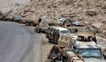 Abandoned Saudi military armored vehicles and combat equipment lined up along a mountainous road near the Yemen border.