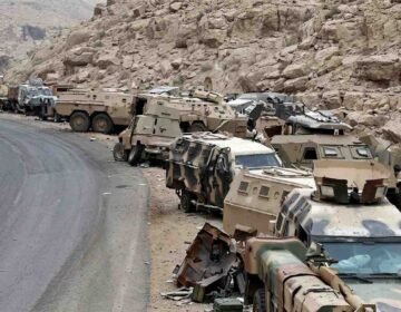 Abandoned Saudi military armored vehicles and combat equipment lined up along a mountainous road near the Yemen border.