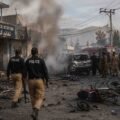 Police and rescue teams respond after a suicide attack at Kabal Police Station in Swat, with smoke, damaged vehicles, and debris visible.