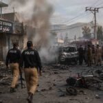 Police and rescue teams respond after a suicide attack at Kabal Police Station in Swat, with smoke, damaged vehicles, and debris visible.