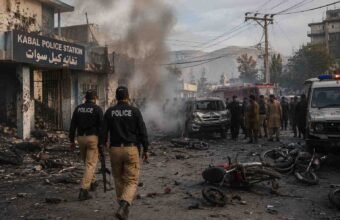 Police and rescue teams respond after a suicide attack at Kabal Police Station in Swat, with smoke, damaged vehicles, and debris visible.
