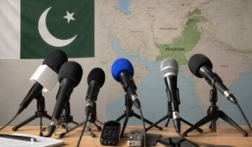 Microphones in a press briefing setup with the Pakistan flag and a map of Pakistan in the background
