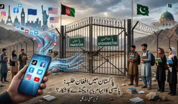 A composite photograph illustrating the complex issues surrounding Afghan students in Pakistan. In the foreground, a hand holds a smartphone displaying social media icons (TikTok, Facebook, Twitter, Instagram, YouTube), with lines of other icons flowing out towards a large, closed, iron border gate. On either side of the gate, groups of young people (students with backpacks and books) stand looking through. The gate itself has signs in Urdu and English reading 'PAKISTAN' and 'AFGHANISTAN'. Above the gate, a cityscape features Western landmarks like the Eiffel Tower, Big Ben, the Statue of Liberty, and the US flag, along with floating text reading 'Propaganda' and 'Policy Ambiguity' next to the source of the social media icons. On the right, a mosque with a green dome is visible, representing Pakistan. Below the central gate, Urdu text reads: "پاکستان میں افغان طلبہ: پالیسی کا ابہام یا پروپیگنڈے کا شکار؟ تحریر صفی اللہ گل" (translation: "Afghan Students in Pakistan: Victims of Policy Ambiguity or Propaganda? By Safiullah Gul"). The background is a dry, mountainous border landscape.