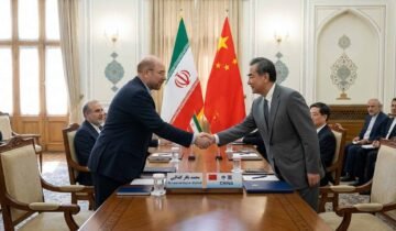 Iranian Parliament Speaker Mohammad Bagher Ghalibaf shaking hands with a Chinese official in front of the Iranian and Chinese flags.