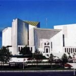 English: Front exterior view of the white marble Supreme Court of Pakistan building in Islamabad under a deep blue sky with a bird flying in the upper-left corner.