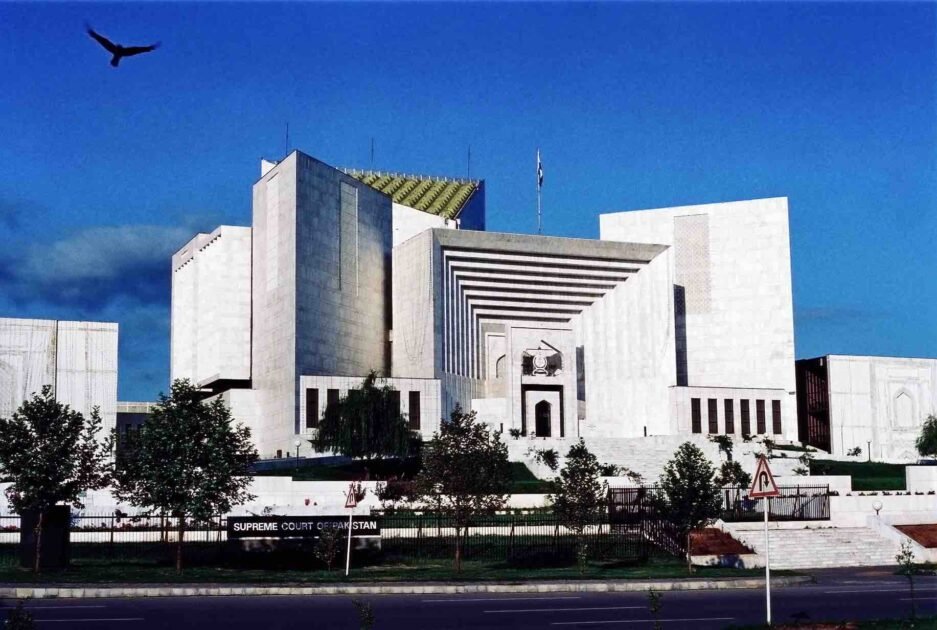 English: Front exterior view of the white marble Supreme Court of Pakistan building in Islamabad under a deep blue sky with a bird flying in the upper-left corner.