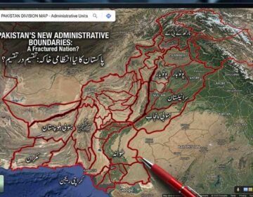 A close-up photograph of a large monitor displaying a satellite map of Pakistan, altered with a complex overlay of thick red lines creating a hypothetical subdivision of the country. At the top of the map, text in English reads: "PAKISTAN'S NEW ADMINISTRATIVE BOUNDARIES: A Fractured Nation?" Below it, Urdu text says: "پاکستان کا نیا انتظامی خاکہ: تقسیم در تقسیم؟" (translated as "Pakistan's New Administrative Plan: Division within Division?"). Numerous Urdu labels partition the map into smaller regions, including "جنوبی پنجاب" (South Punjab), "سرائیکستان" (Saraikistan), "پوٹوہار" (Pothohar), "مکران" (Makran), and "کراچی ریجن" (Karachi Region). Labels for adjacent territories like "INDIA", "AFGHANISTAN", "IRAN", "BALOMISTAN", "KARTAN", and "BHOJO" are also visible. A red pen tip is shown in the foreground near the bottom-center, poised near where "TANDO" (partially obscured) is written. The user interface mimics Google Maps, with a search bar and map controls. The background is a blurred view of multiple screens in a newsroom or control room.