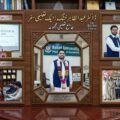 A sophisticated, multi-panel composite image in an ornate wooden frame, presented on a polished desk in a formal setting, celebrating the academic milestones and awards of Dr. Abdul Zahir Khattak. Key scenes include a research presentation, receiving a prestigious HEC award, research collaboration, and a group photo with recognized faculty from the Department of Economics at Kohat University. Contains extensive Urdu and English text confirming PhD and HEC awards.