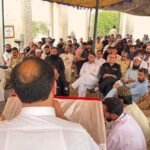 A wide-angle photograph of a large gathering under an outdoor canopy in KP, Pakistan, showing former Khasadar Force personnel and civilians protesting for their integration rights into the regular police force.