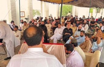 A wide-angle photograph of a large gathering under an outdoor canopy in KP, Pakistan, showing former Khasadar Force personnel and civilians protesting for their integration rights into the regular police force.