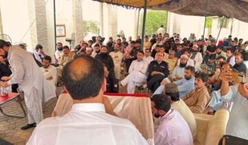 A wide-angle photograph of a large gathering under an outdoor canopy in KP, Pakistan, showing former Khasadar Force personnel and civilians protesting for their integration rights into the regular police force.
