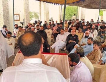 A wide-angle photograph of a large gathering under an outdoor canopy in KP, Pakistan, showing former Khasadar Force personnel and civilians protesting for their integration rights into the regular police force.
