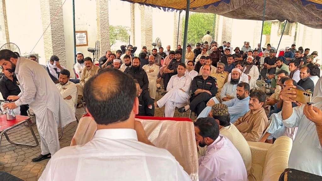 A wide-angle photograph of a large gathering under an outdoor canopy in KP, Pakistan, showing former Khasadar Force personnel and civilians protesting for their integration rights into the regular police force.