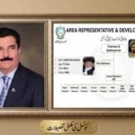 A combined photograph within a decorative wooden frame. The left panel is a formal portrait of a man in a navy blue suit with a Pakistani flag pin. The right panel is an organizational flowchart for the 'Area Representative & Development Council' for Khyber Pakhtunkhwa (KP). The chart shows Shoukat Ullah Khan as Chairman and Malik Khan Marjan as Vice Chairman, with a list of lower-level council divisions and member numbers. The bottom plaque has Urdu text 'کونسل کی مکمل تفصیلات'.